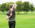 Ein Mann in Sportkleidung macht Dehnübungen im Park.