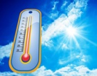 Ein überdimensionales Thermometer im Vordergrung vor einem blauen Sommerhimmel. Symbolbild für Sommerhitze.