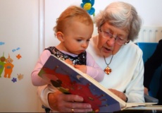 Eine Oma liest ihrem Enkelkind aus einem Buch vor.