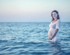 Eine schwangere Frau steht im Meer.