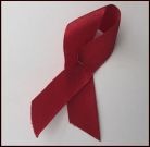 Ein rotes Band als Schleifre gelegt. Symbild für AIDS und andere sexuell übertragbare Infektionen.