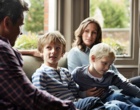 Eine vierköpfige Familie sitzt auf einem Sofa.