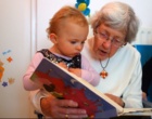 Eine Oma liest ihrem Enkelkind aus einem Buch vor.
