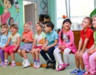 Lachende Kita-Kinder sitzen auf einer Bank.