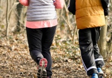 Zwei Personen joggen durch einen Wald.