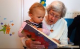Eine Oma liest ihrem Enkelkind aus einem Buch vor.