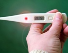 Eine Hand hält ein Fieberthermometer. Symbolbild für Fieber.