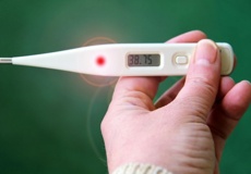 Eine Hand hält ein Fieberthermometer. Symbolbild für Fieber.