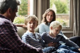 Eine vierköpfige Familie sitzt auf einem Sofa.