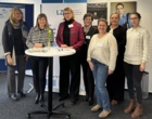 Mehrere Frauen stehen um einen Stehtisch herum.