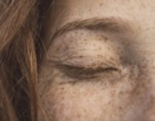 Ausschnitt eines Gesichts einer rothaarigen Frau mit Sommersprossen.