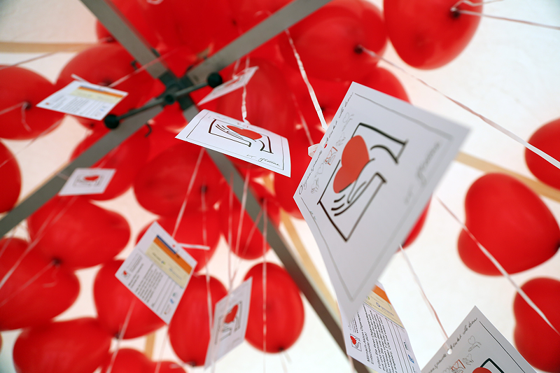 Fliegende rote Luftballons in Herzform mit Zetteln dran. Symbolbild für Organspende.